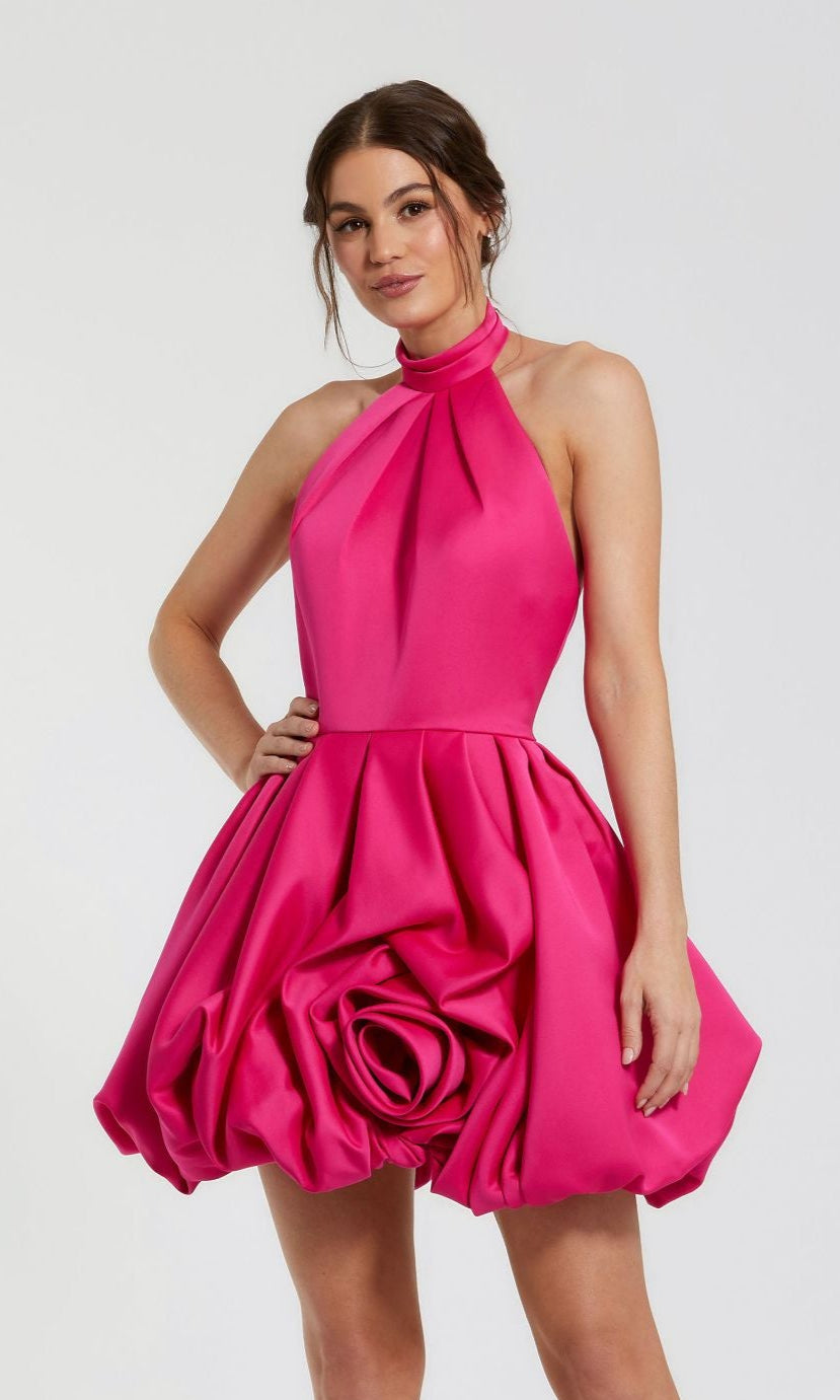 A woman wears the Mac Duggal 20707 Short Bubble-Hem Party Dress in bright pink, featuring a voluminous skirt and large rosette detail, standing against a plain background.